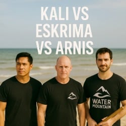 Three martial artists stand on a beach after training, wearing Water Mountain logo t-shirts, under the text "Kali vs Escrima vs Arnis."